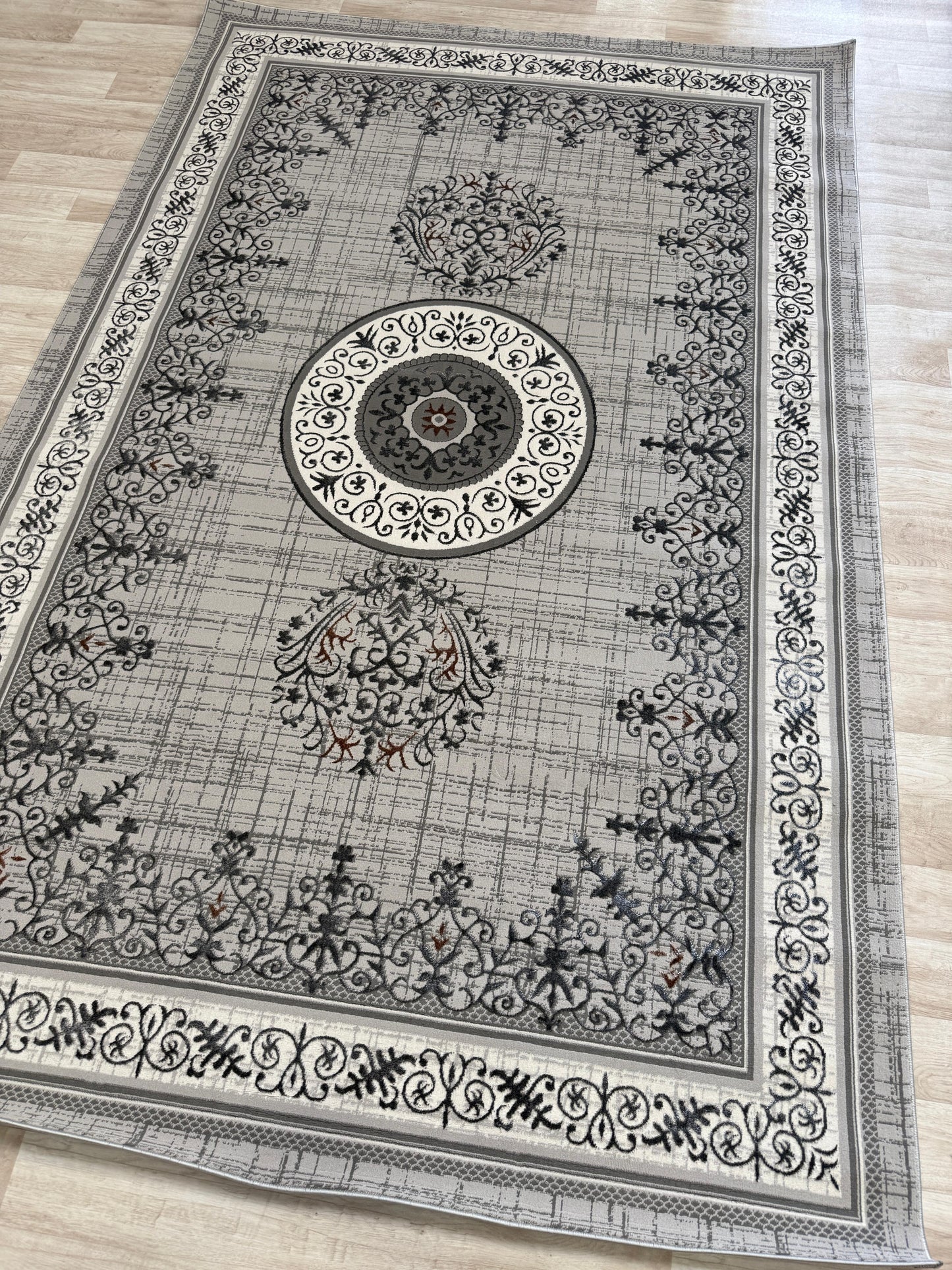 Decorative rug with intricate black patterns on a light wood floor